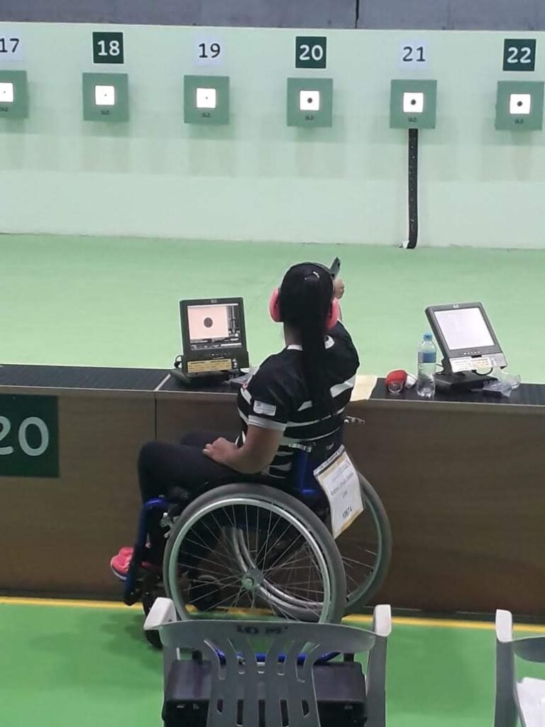 Descrição da imagem #pracegover: A paratleta Andreia Úrsula durante torneio de tiro esportivo. Andreia está sentada, em sua cadeira de rodas. Fim da descrição.
