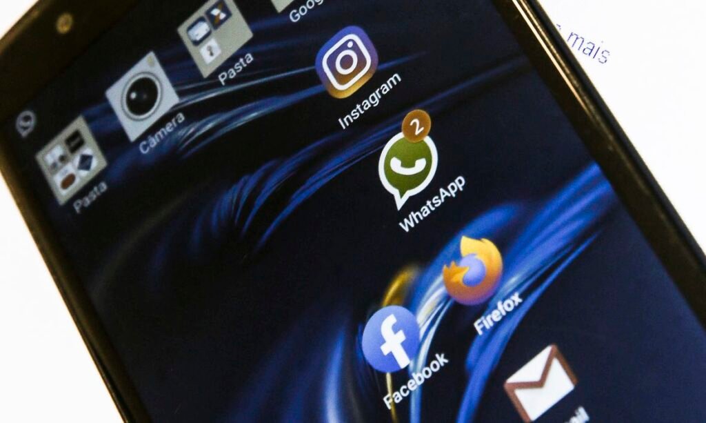 Descrição da imagem #pracegover: A tela de um celular com a imagem de alguns aplicativos. Fim da descrição.