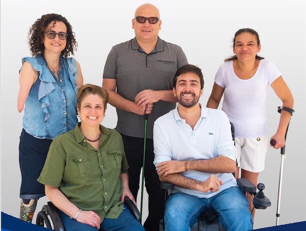 Descrição da imagem #pracegover: Grupo de candidatos do Todos pela acessibilidade. Na frente estão Selma Rodeguero e Bruno Beraldin, cadeirantes. Atrás, em pé, estão Carolina Paraguaçu, que tem malformação congênita nos braços; Sonny Polito, que é cego e Fátima Lima, que tem esclerose múltipla e utiliza muletas. Fim da descrição. 