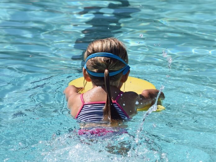 Descrição da imagem #pracegover: Uma menina está na piscina e pratica natação. Fim da descrição.