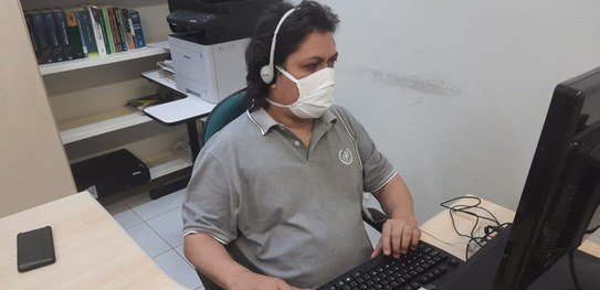 Descrição da imagem #pracegover: Raimundo Nonato durante o trabalho. Ele está sentado na mesa usando o computador. Fim da descrição.