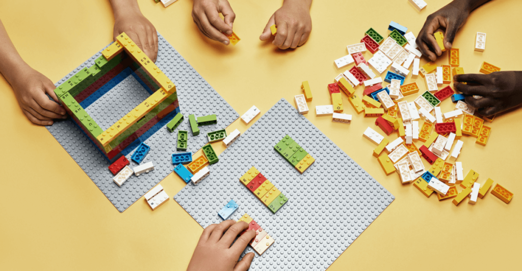 Descrição da imagem #pracegover: Mãos de crianças brincando com os blocos de montar LEGO Braille Bricks. Fim da descrição.