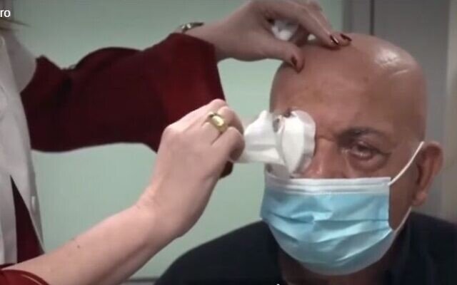 Descrição da imagem #pracegover: Jamal Furani, primeiro homem cego a voltar a enxergar após receber um implante de córnea artificial, retirando o curativo do olho. Fim da descrição.