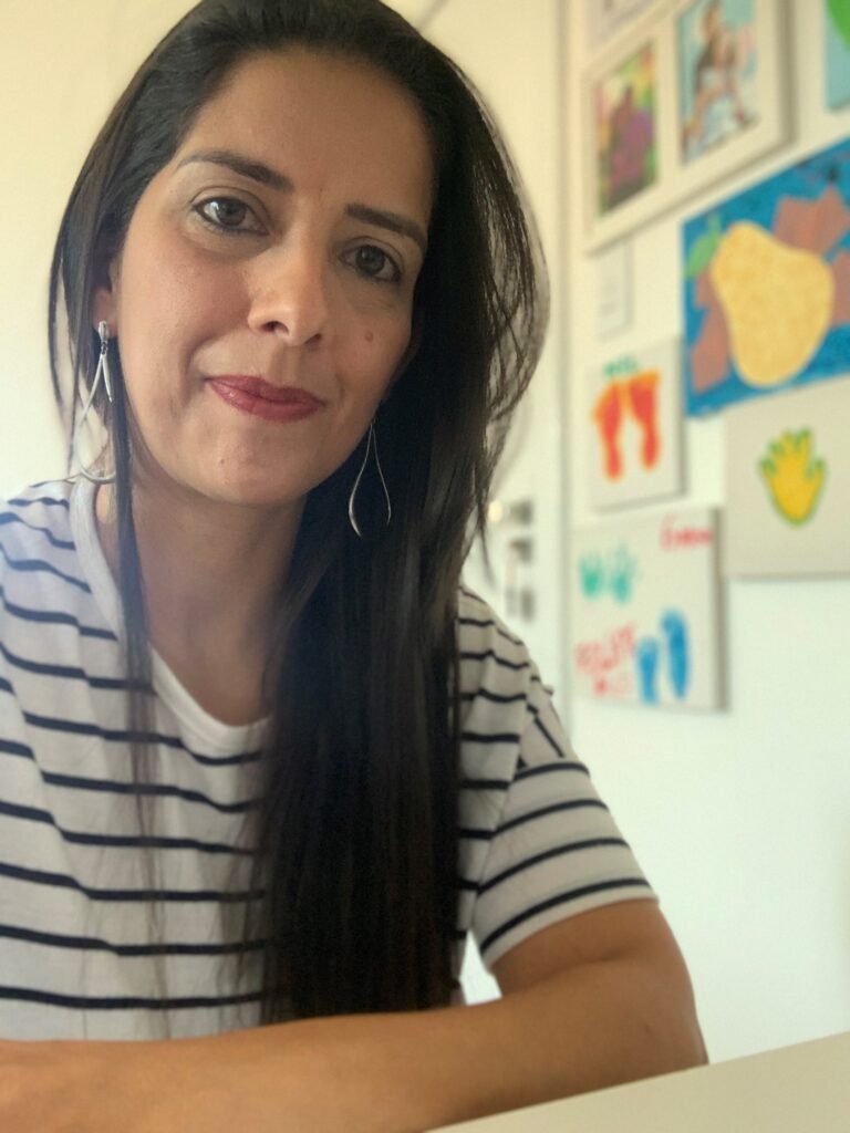 Descrição da imagem #pracegover: Foto da Mirela. Ela é uma mulher morena, de cabelos pretos, lisos e compridos. Ela usa uma camiseta listrada em preto e branco. Fim da descrição.