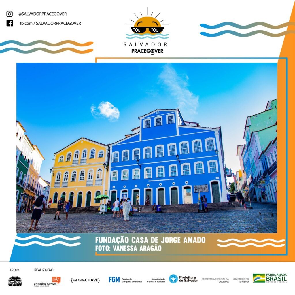 Descrição da imagem #pracegover: Foto de um ponto turístico da cidade de Salvador. Sob um céu intensamente azul quase sem nuvens, numa praça de paralelepípedos com algumas pessoas, erguem-se, ladeados por duas vielas com casas coloridas, dois casarões de dois andares com muitas janelas e portas, o primeiro amarelo e o segundo, bem maior, com fachada azul, ambos com acesso por uma ampla escadaria cinzenta. Fim da descrição.