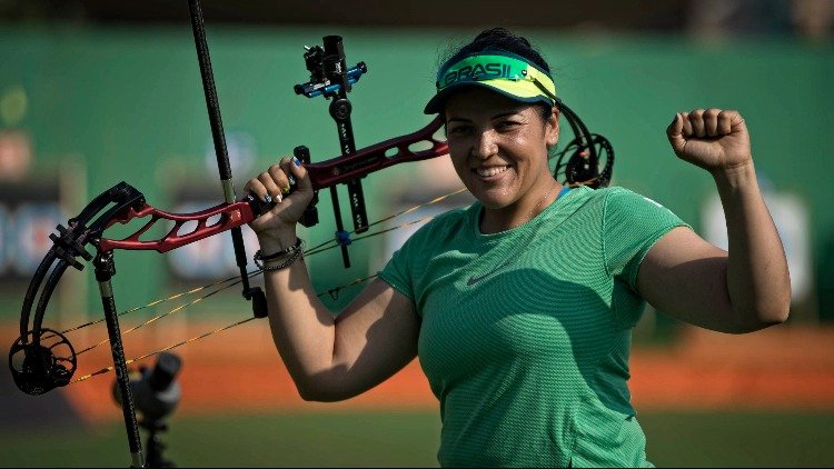 Descrição da imagem #pracegover: A paratleta Jane Karla durante uma de suas disputas. Jane é uma mulher branca com cabelos castanhos. Ela está segurando um arco. Fim da descrição.