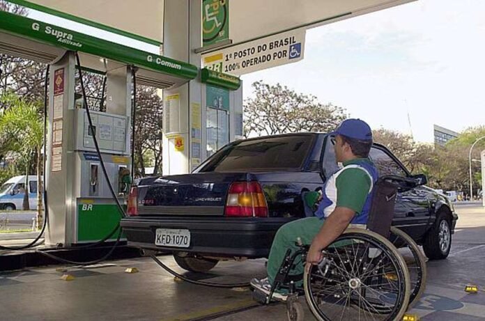 Descrição da imagem #pracegover: Foto de um homem com deficiência física trabalhando em um posto de gasolina. O homem é negro. Ele está abastecendo um carro. Fim da descrição.