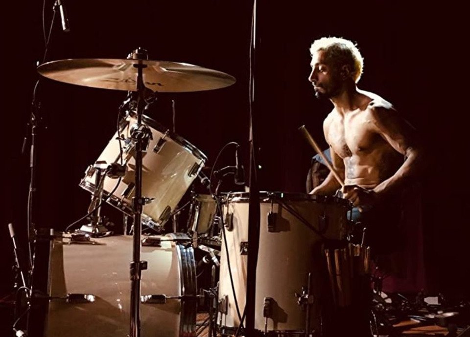 Descrição da imagem #pracegover: Cena do filme O som do silêncio. O protagonista está tocando bateria. Fim da descrição.