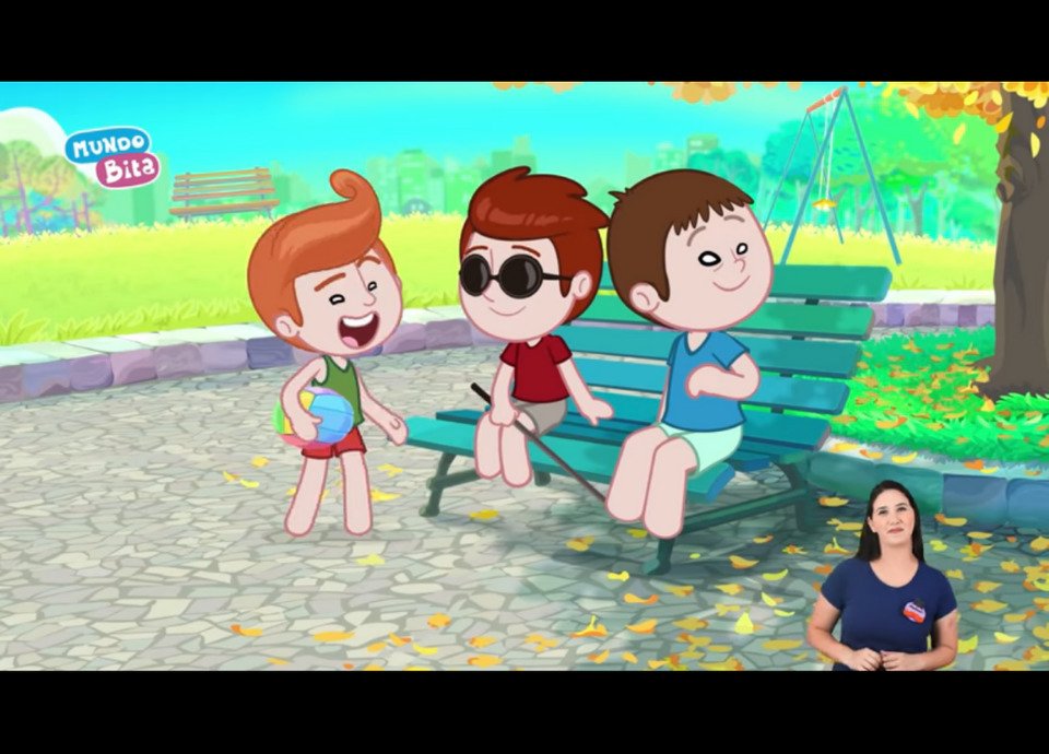 Descrição da imagem: Imagem do clipe. Na arte, três crianças estão em uma praça. Uma delas é cega e está usando óculos e guia. No canto inferior esquerdo está a intérprete de Libras. Fim da descrição.