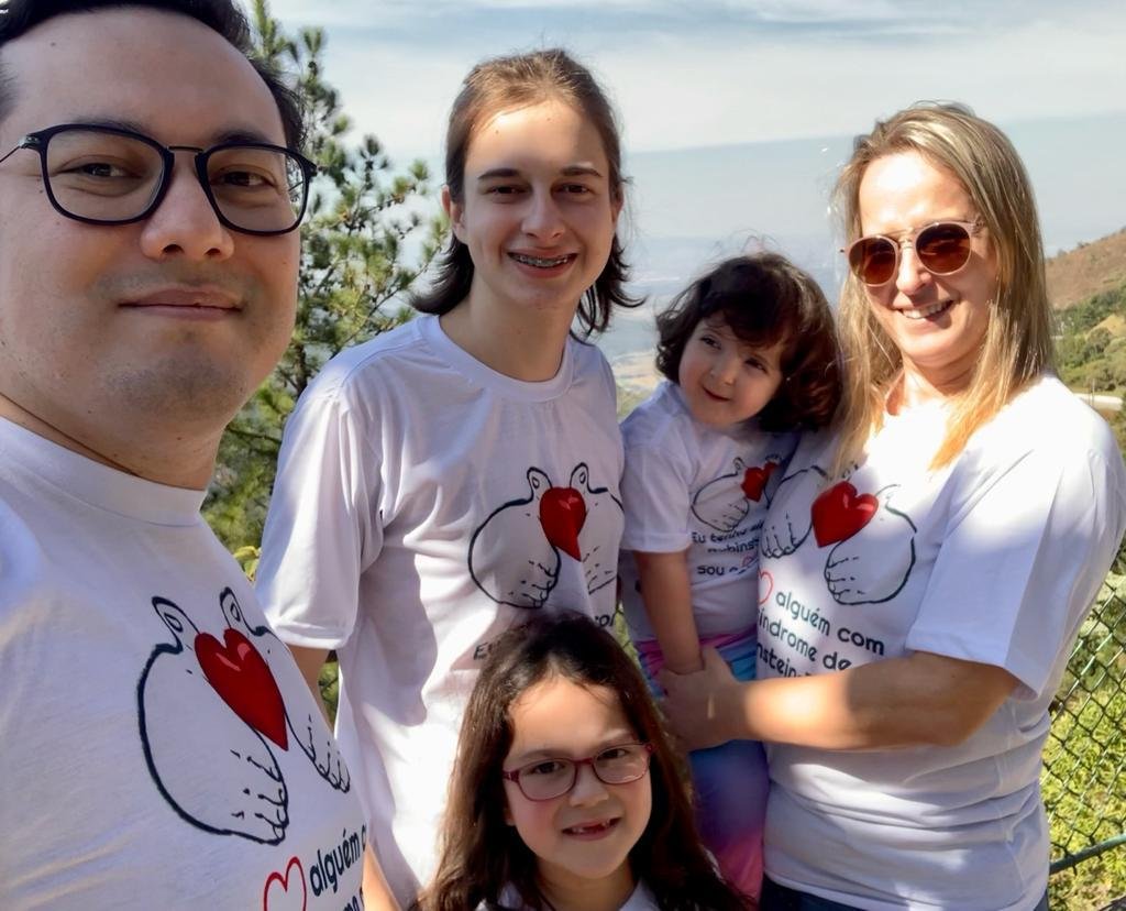 Descrição da imagem: Foto da família. Mãe, pai e três filhos. Todos vestem a camisetas iguais. Fim da descrição.