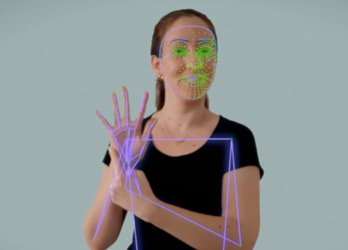 Descrição da imagem: Imagem da tecnologia Motion. Uma mulher fazendo um sinal da língua de sinais. Sobre a imagem dela estão marcações digitais que representam a leitura do sinal. Fim da descrição.