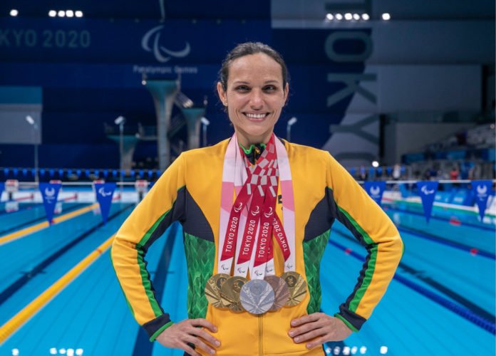 Descrição da imagem: Foto da atleta Maria Carolina com suas 6 medalhas penduradas no pescoço. Fim da descrição.