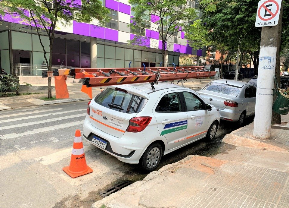 Descrição da imagem: Foto de um carro estacionado em local proibido, atrapalhando a passagem de pedestres. Fim da descrição.