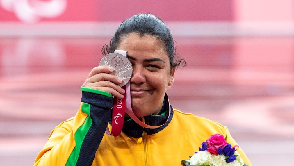 Descrição da imagem: Foto da atleta Marivana Oliveira exibindo sua medalha de prata. Fim da descrição.