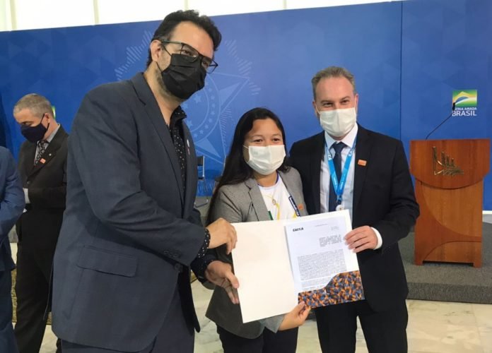#descriçãodaimagem: Foto da presidente da CBDS, Diana Kyosen com o diretor administrativo Carlos Henrique e o vice-presidente da CAIXA, Matheus Neves Sinibaldi. Eles estão segurando o termo de patrocínio. Fim da descrição.