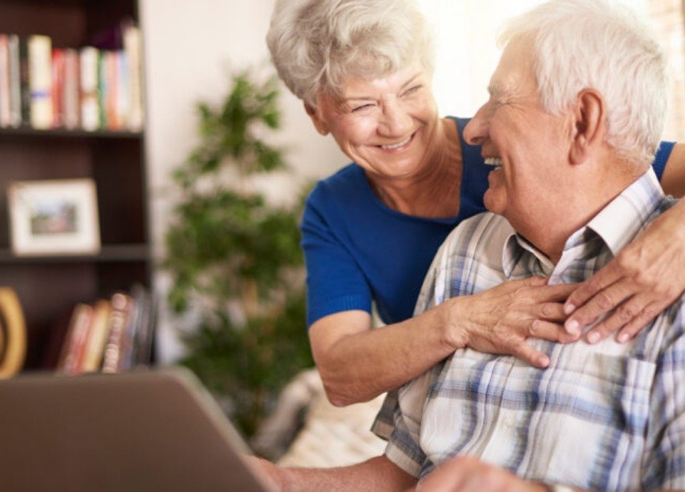 #descriçãodaimagem: foto de um casal de idosos. Eles estão usando o computador. Fim da descrição.