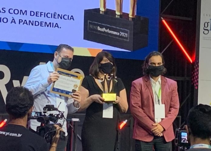 #descriçãodaimagem: foto da equipe do Instituto Jô Clemente recebendo a premiação. Três representantes da instituição estão no palco do evento. Fim da descrição.