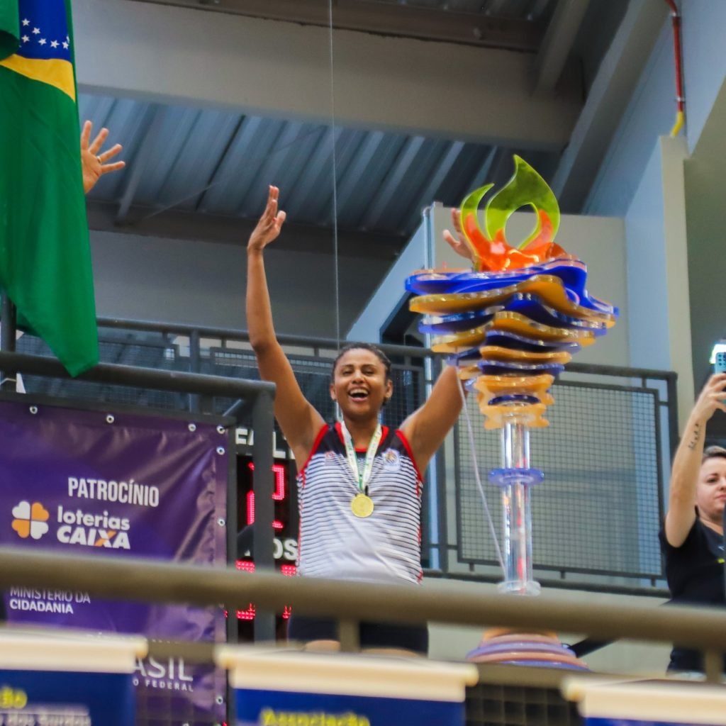 #descriçãodaimagem: foto da atleta Natália Santos apagando a tocha olímpica. Fim da descrição.