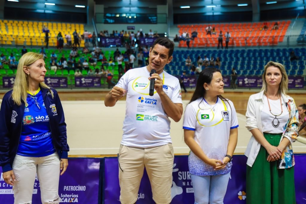 #descriçãodaimagem: foto do secretário Guedes durante seu discurso. Ao seu lado estão Kátia Machado, secretária de esportes de São José, Diana Kyosen, presidente da CBDS e Giselle Chirolli, diretora da Secretaria Nacional do Paradesporto. Fim da descrição.