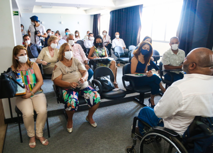 Descrição da imagem: Foto do público presente no evento de assinatura do termo de parceria. Em primeiro plano, está o secretário executivo da Pessoa com Deficiência, Salomão Júnior, que é cadeirante. Fim da descrição.