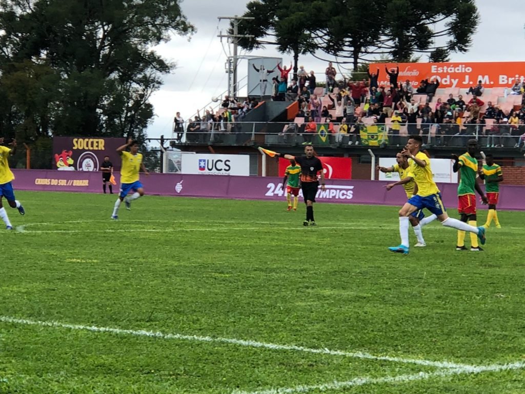 Descrição da imagem: foto do momento do gol do Brasil na partida. Os jogadores brasileiros comemoram, enquanto o árbitro aponta para o meio do campo. Fim da descrição.