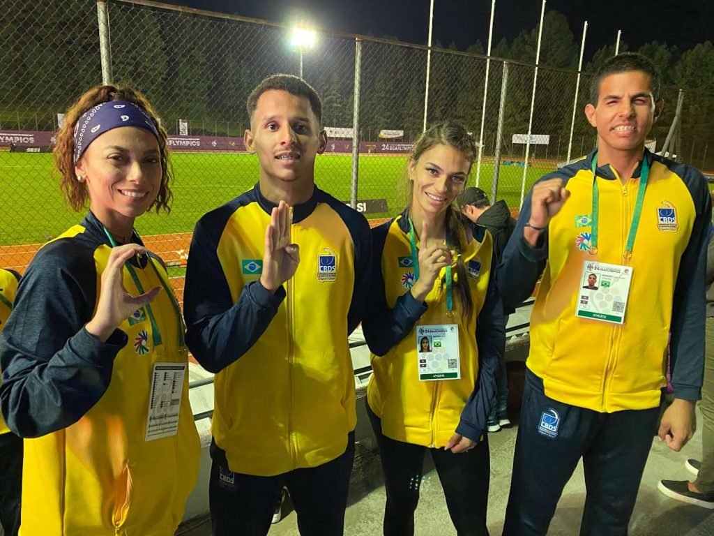 Descrição da imagem: foto dos surdoatletas que disputaram a final do revezamento 4x400m. Eles estão lado a lado e fazem as letras CBDS, com as mãos. Todos usam o uniforme amarelo da seleção brasileira. Fim da descrição.