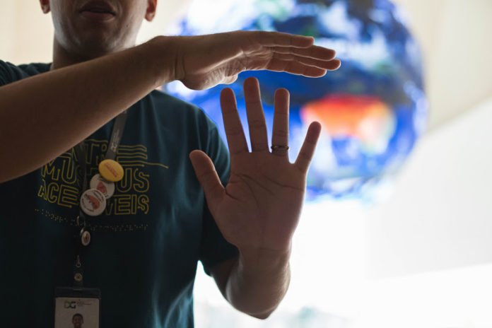 Descrição da imagem: foto de um intérprete de Libras durante atividade no Museu do Amanhã. Fim da descrição.