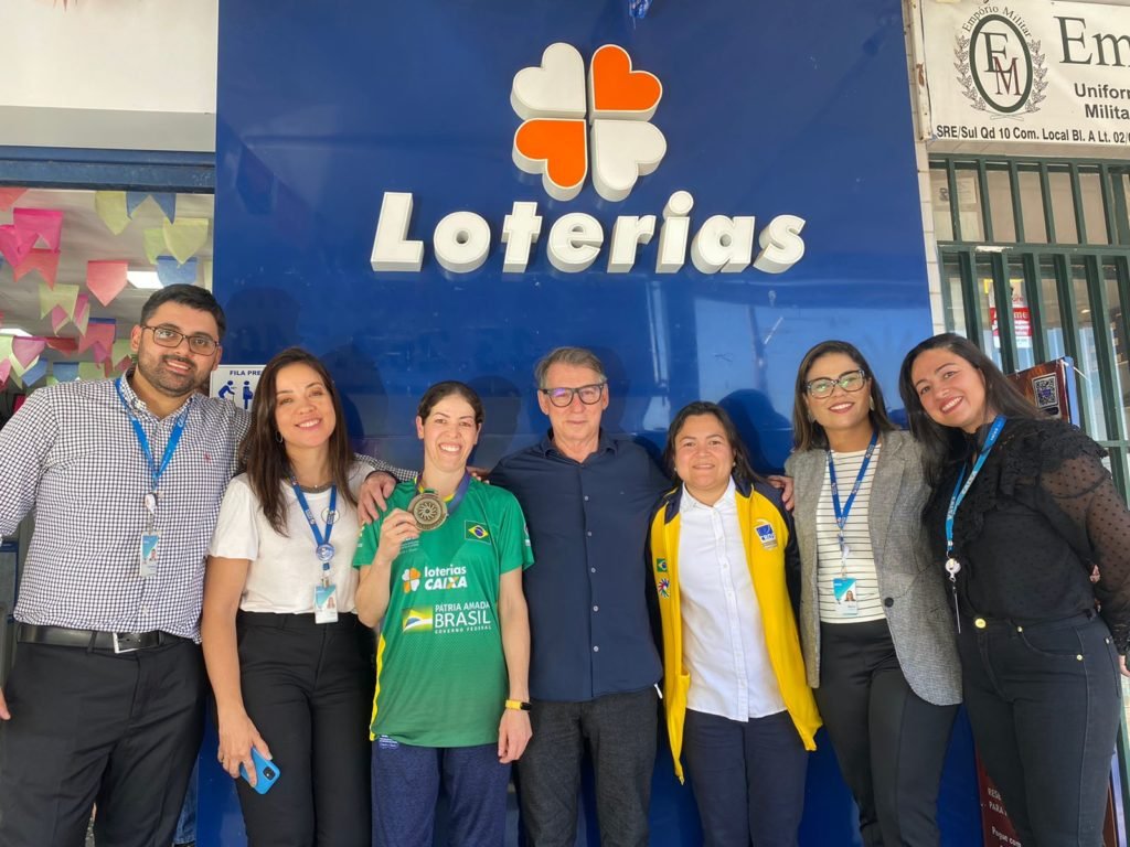 Descrição da imagem: foto da presidente da CBDS, Diana Kyosen e da atleta Vanderleia com representantes das Loterias Caixa, durante gravação de um comercial. Fim da descrição.