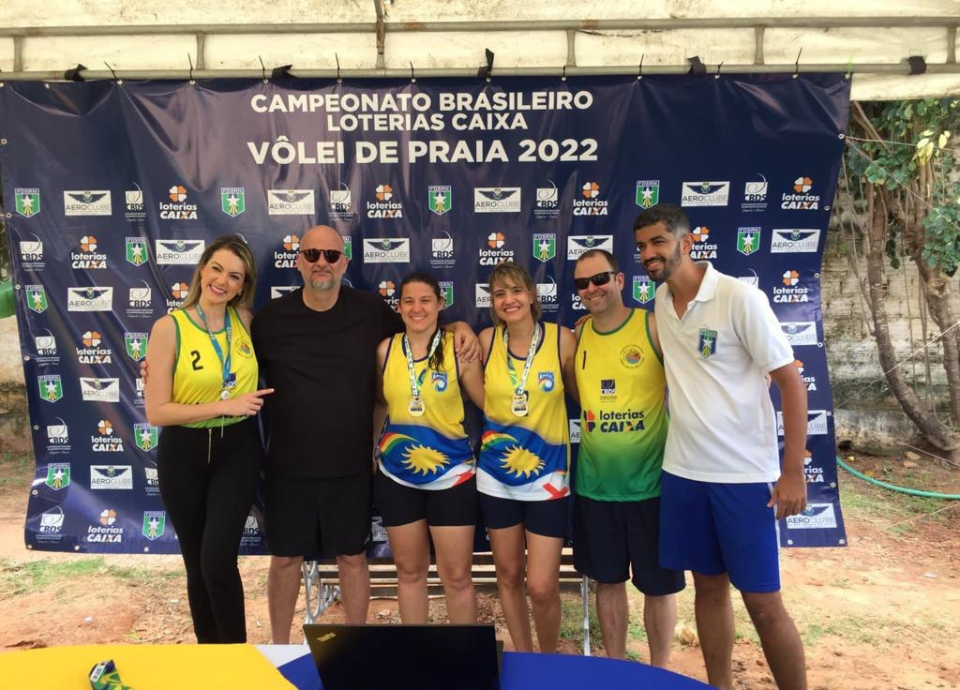 Descrição da imagem: foto das medalhistas do campeonato de vôlei de praia, durante a premiação. Fim da descrição.