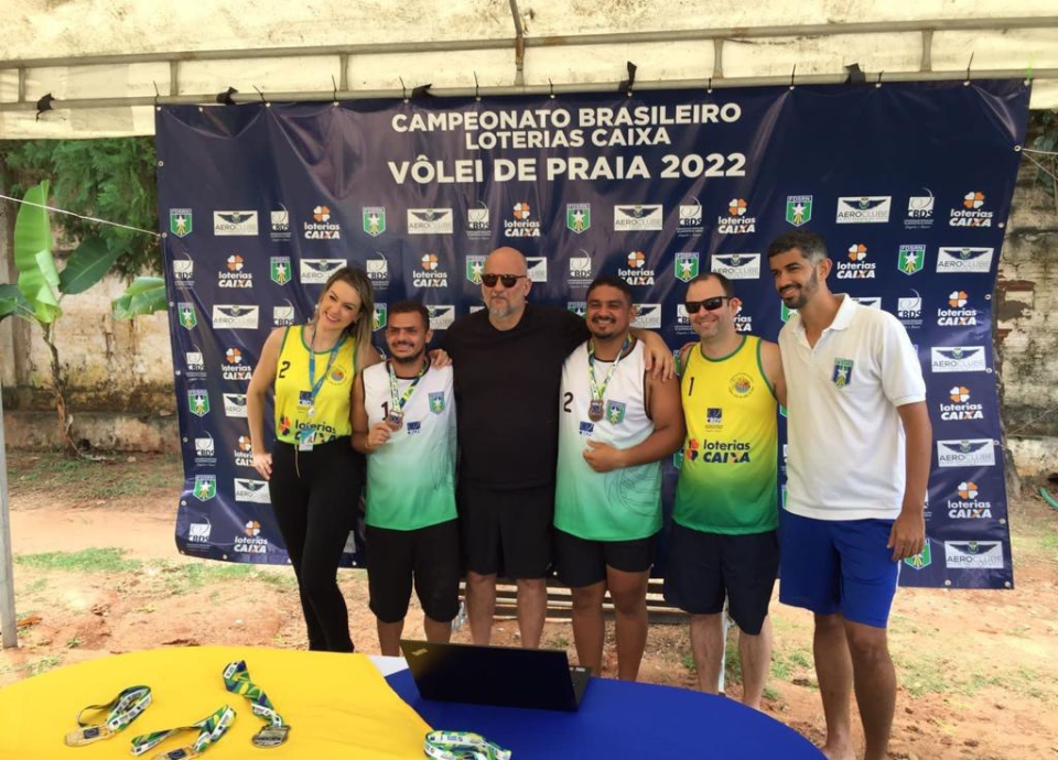 Descrição da imagem: foto dos medalhistas do campeonato de vôlei de praia, durante a premiação. Fim da descrição.