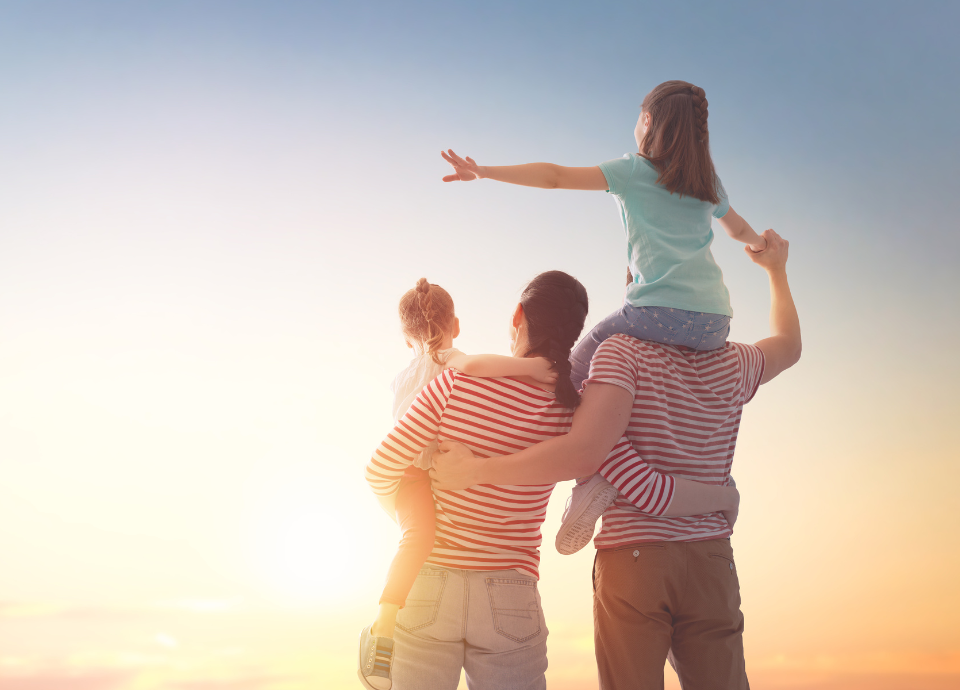 Descrição da imagem: foto de uma família. Um casal com duas crianças, olhando o horizonte, com o nascer do sol. Fim da descrição.