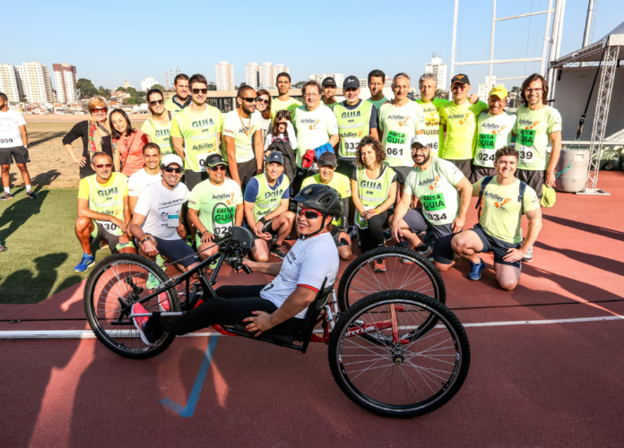Descrição da imagem: foto de um grupo de participantes da 1ª edição da Corrida dos Sonhos. Eles estão na pista de atletismo do CT Paralímpico. Fim da descrição.