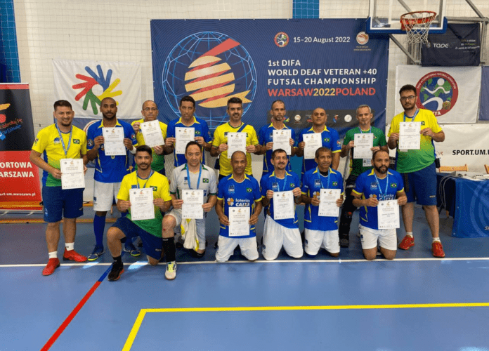Descrição da imagem: foto dos surdoatletas da Seleção Brasileira Master de Futsal de Surdos. Eles estão perfilados e seguram o título de 5º colocado. Fim da descrição.