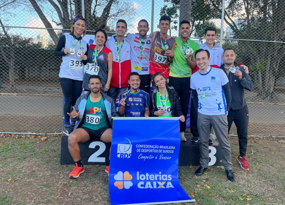 Descrição da imagem: foto dos atletas e da equipe de Atletismo. Fim da descrição.
