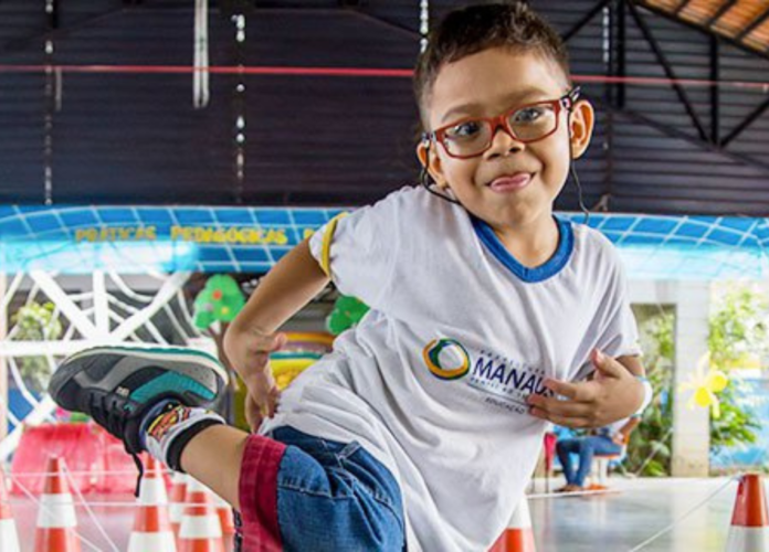 Descrição da imagem: foto de um menino brincando em uma quadra. Ele está sorrindo. Fim da descrição.