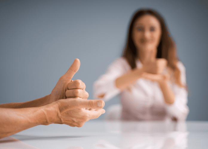 Descrição da imagem: foto de duas pessoas conversando em Libras. Fim da descrição.