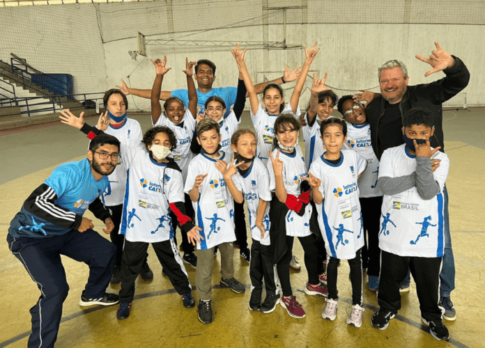 Descrição da imagem: foto dos alunos e da comissão técnica da escolinha de Futsal. Fim da descrição.