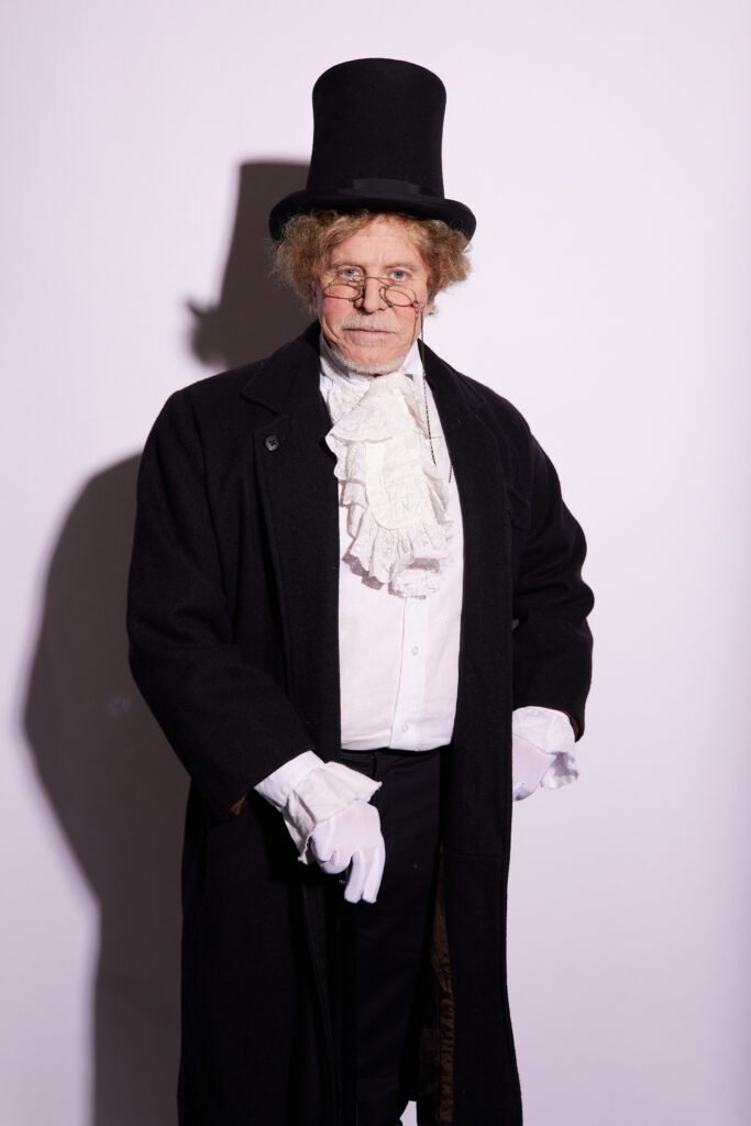 Descrição da imagem: foto de uma personagem do musical. Um homem cacterizado. Fim da descrição.