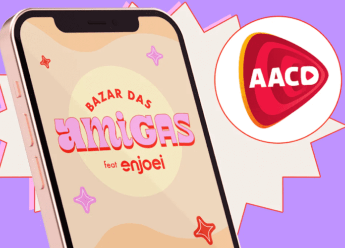 Descrição da imagem: arte de divulgação do bazar solidário. A arte tem a imagem de um celular. Em sua tela está escrito: Bazar das Amigas Enjoei. Ao lado está o logo da AACD, dentro de um círculo. A imagem tem fundo lilás. Fim da descrição.