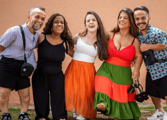 Descrição da imagem: foto de cinco modelos com nanismo vestindo as roupas da marca. Fim da descrição.