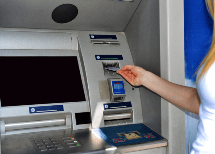 Descrição da imagem: foto de uma mulher usando o caixa eletrônico do banco. Fim da descrição.