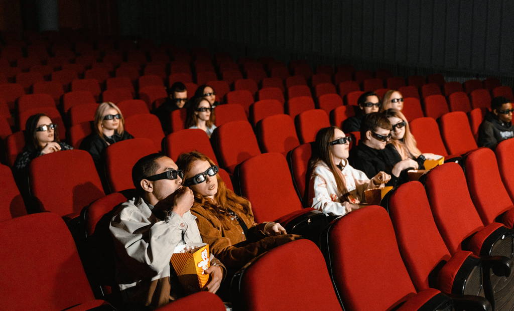 #descricaodaimagem #pratodosverem foto de uma sala de cinema com algumas pessoas assistindo a um filme.