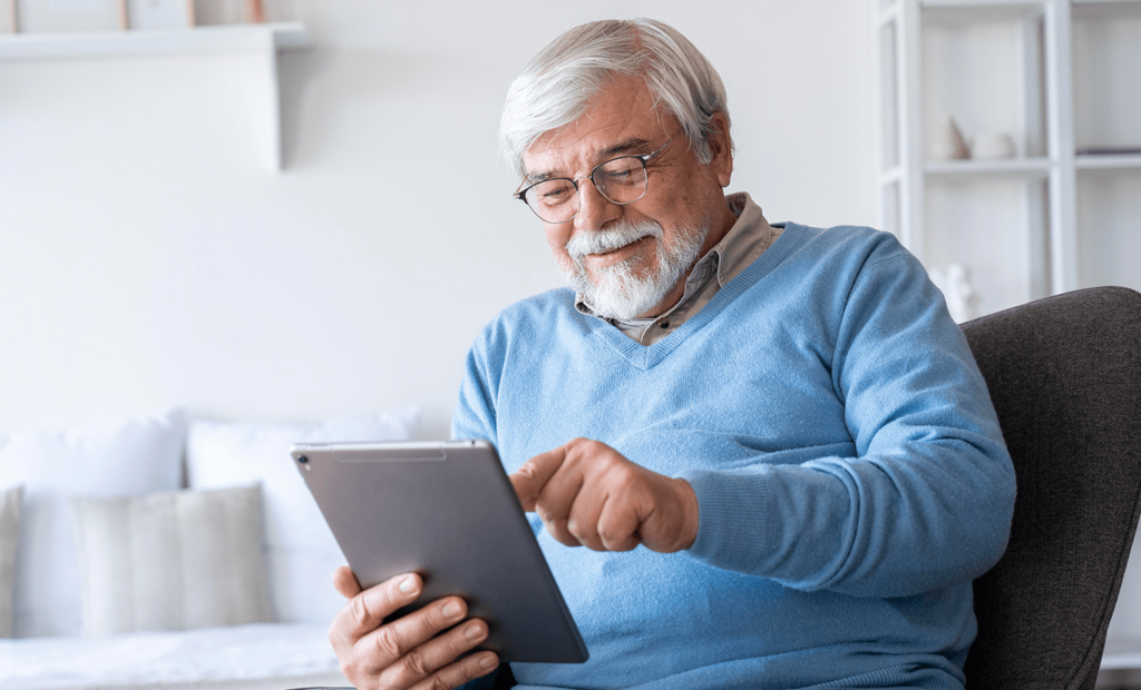 #descricaodaimagem #pratodosverem foto de um homem idoso usando um tablet. Fim da descrição.