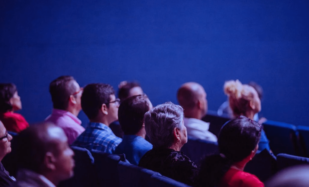 #descricaodaimagem #pratodosverem foto de uma sala de cinema e algumas pessoas assistindo o filme.