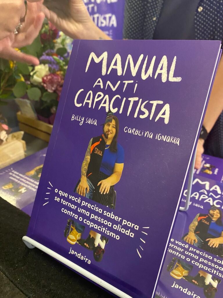 #descricaodaimagem #pratodosverem imagem de capa do livro. O livro tem capa roxa com o título: Manual Anticapacitista. Em destaque está uma montagem da foto de Carol e Billy. Fim da descrição.