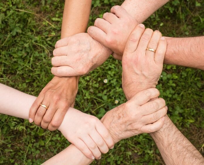 #descricaodaimagem #pratodosverem foto de um grupo de pessoas segurando nos pulsos, uns dos outros.