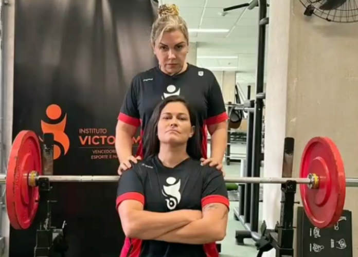 #descricaodaimagem #pratodosverem foto de Carol Basílio com sua técnica, Catia Portilho, durante treino de Powerlifting. A técnica está de pé, atrás da Carol, que está sentada. Entre elas, atrás de Carol, está o peso.