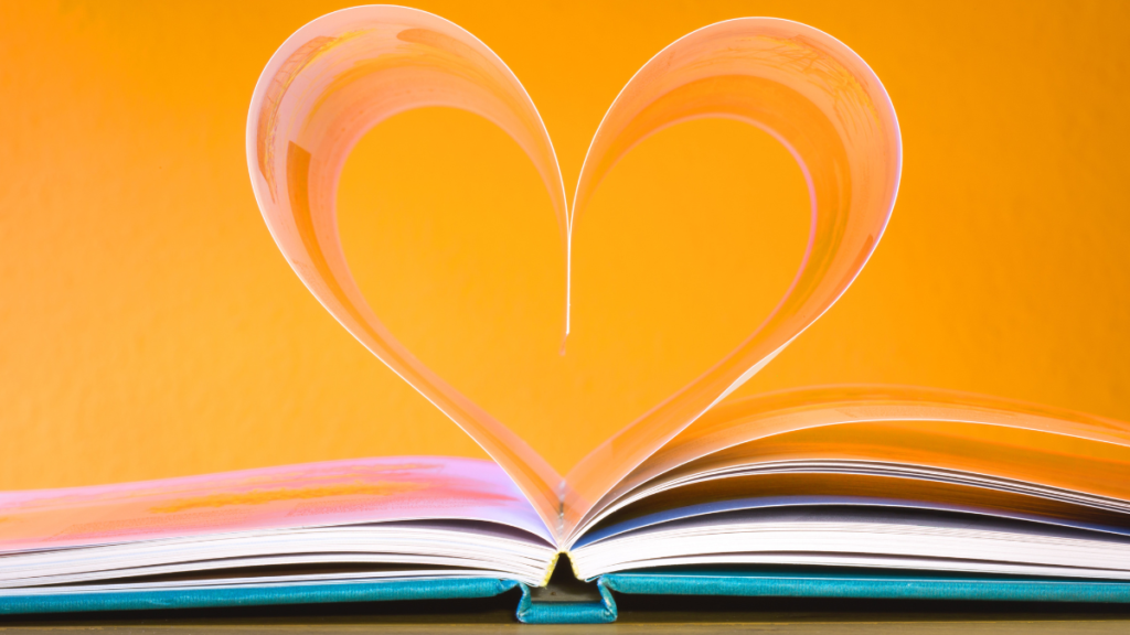 #descricaodaimagem #pratodosverem foto de um livro aberto. Suas páginas formam um coração. A imagem tem fundo laranja.