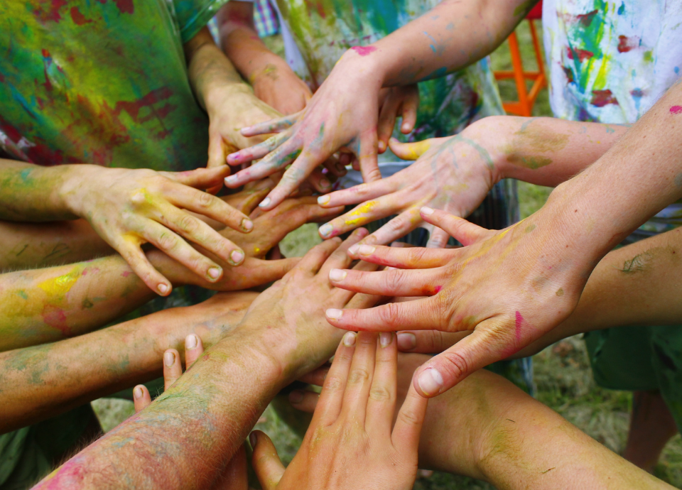 #descricaodaimagem #pratodosverem foto de várias mãos de crianças unidas no centro. As mãos estão pintadas com tinta colorida.