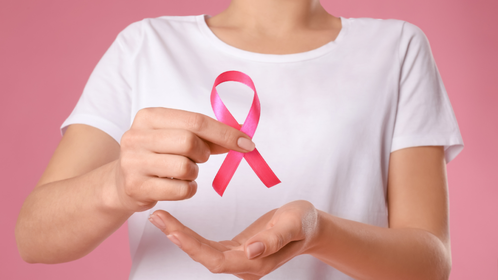 #descricaodaimagem #pratodosverem foto de uma mulher segurando um laço rosa.